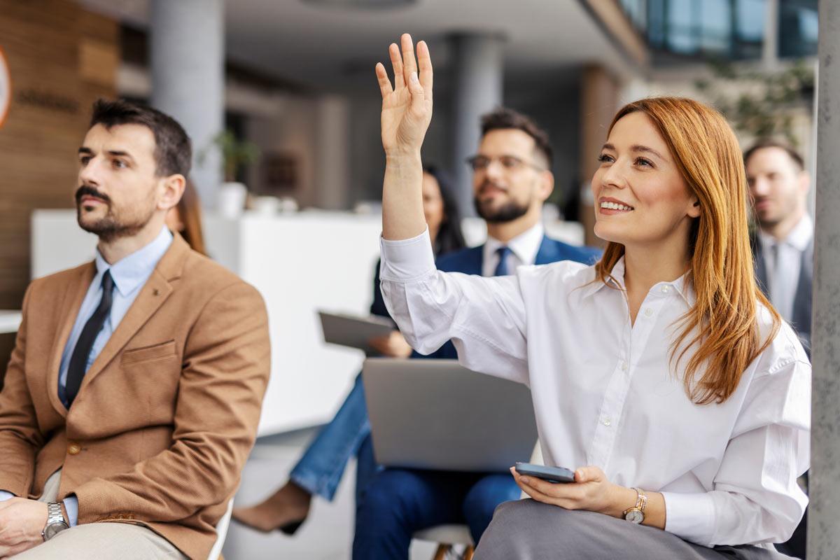 Female raising hand to ask question during meeting